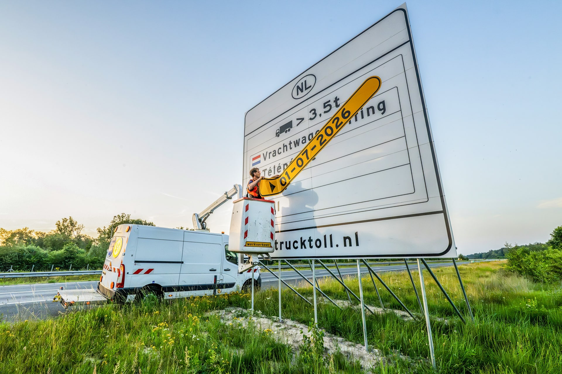 Worker removes date strip from truck toll sign